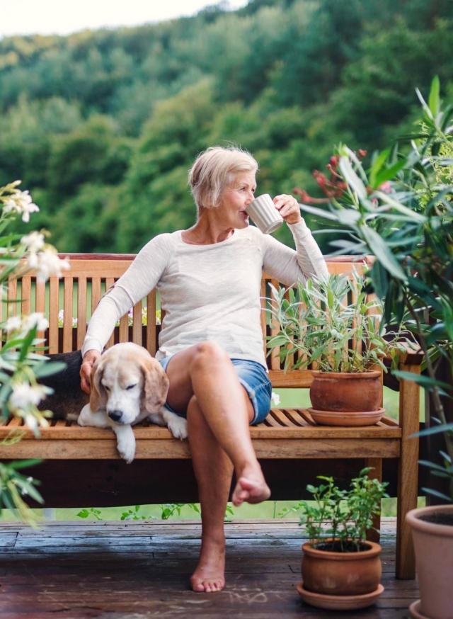 Woman on bench drinking coffee with her dog